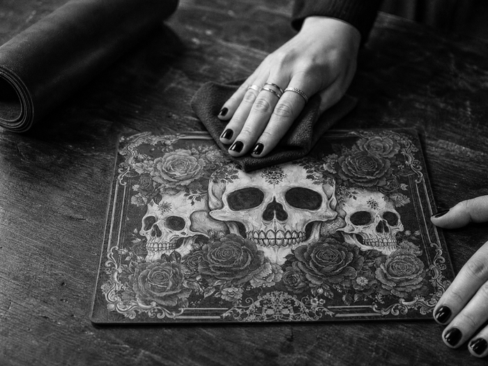 Hands smoothing the printed bloodrose artwork panel on the worktable